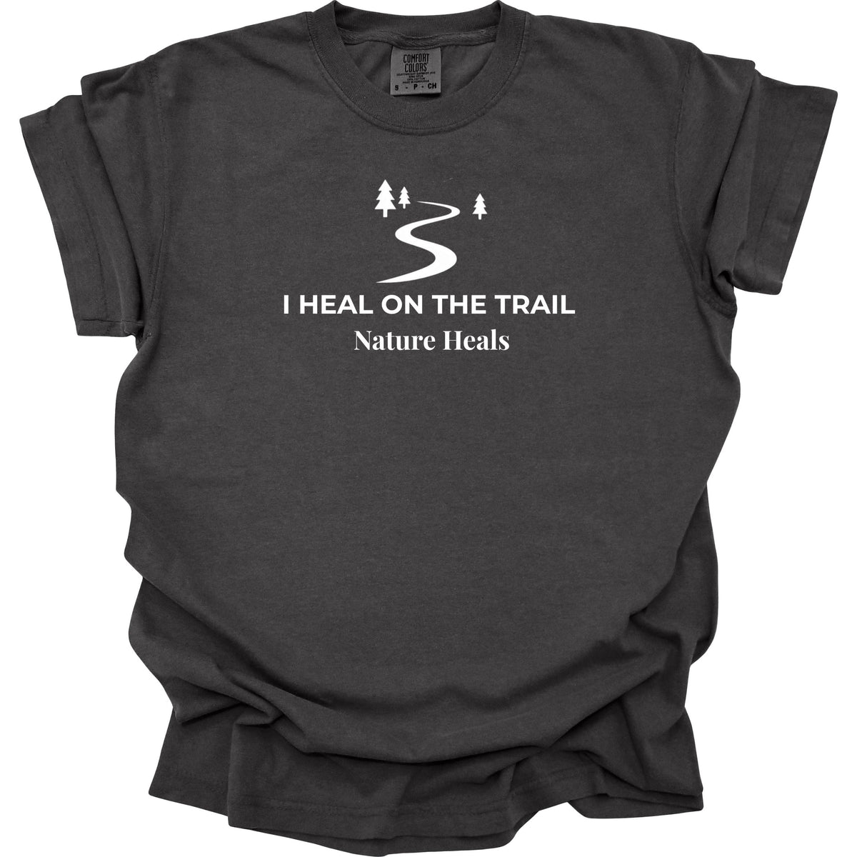 A dark charcoal gray t-shirt featuring white text that reads 'I HEAL ON THE TRAIL Nature Heals' and a trail icon graphic, with a white background.