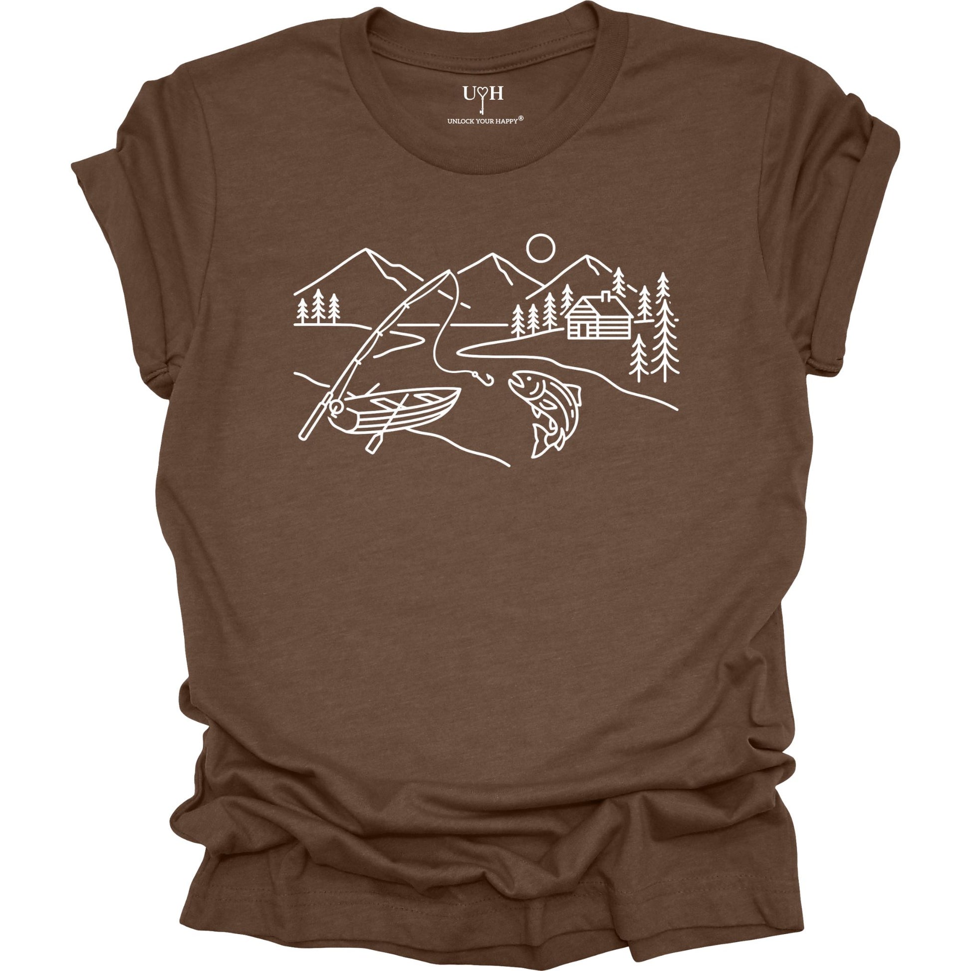 Brown t-shirt featuring a minimalist white line art fishing design with mountains, river, canoe, fish, cabin, and pine trees.