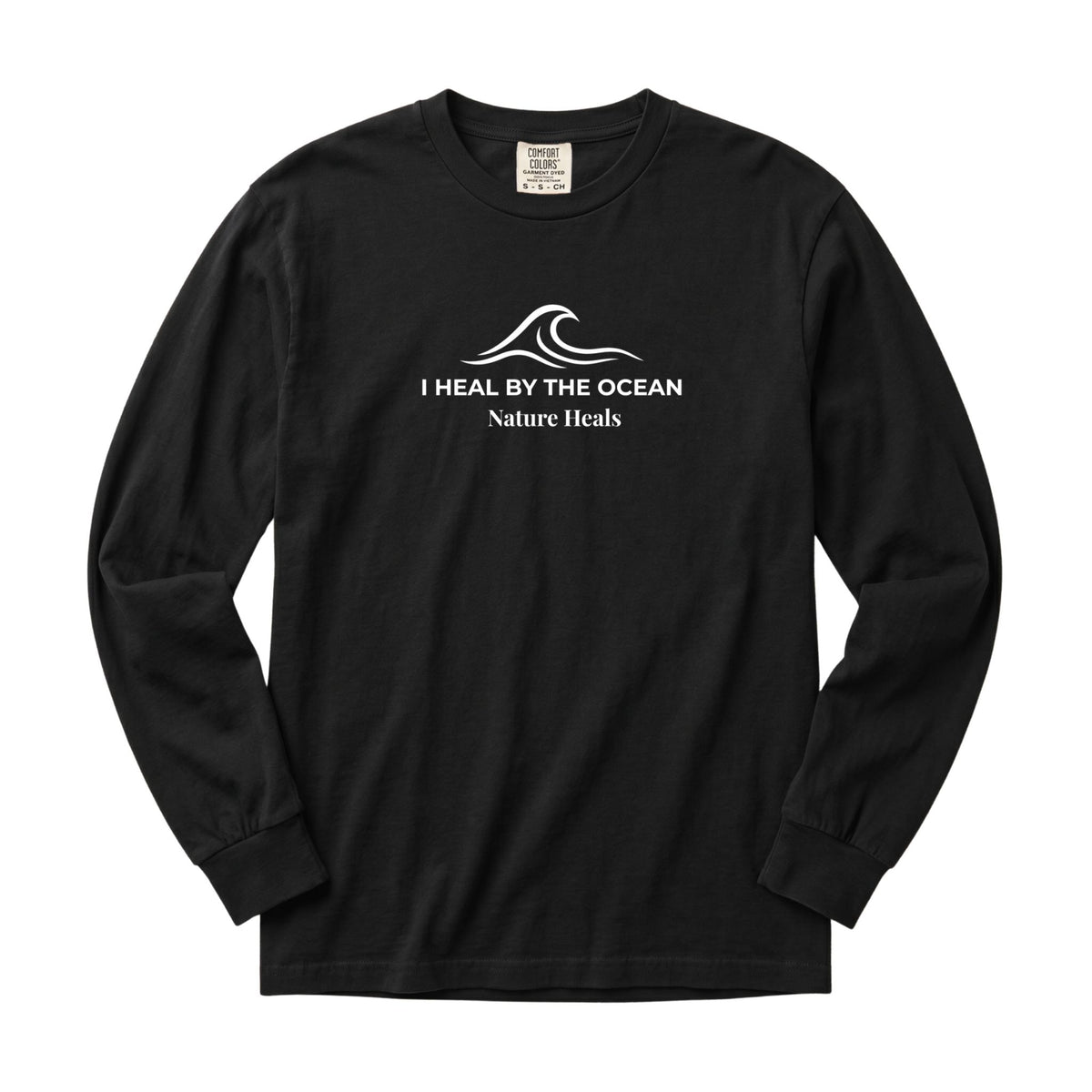 A black long-sleeve t-shirt with a white graphic on the chest showing an ocean wave and the text 'I HEAL BY THE OCEAN  Nature Heals'.