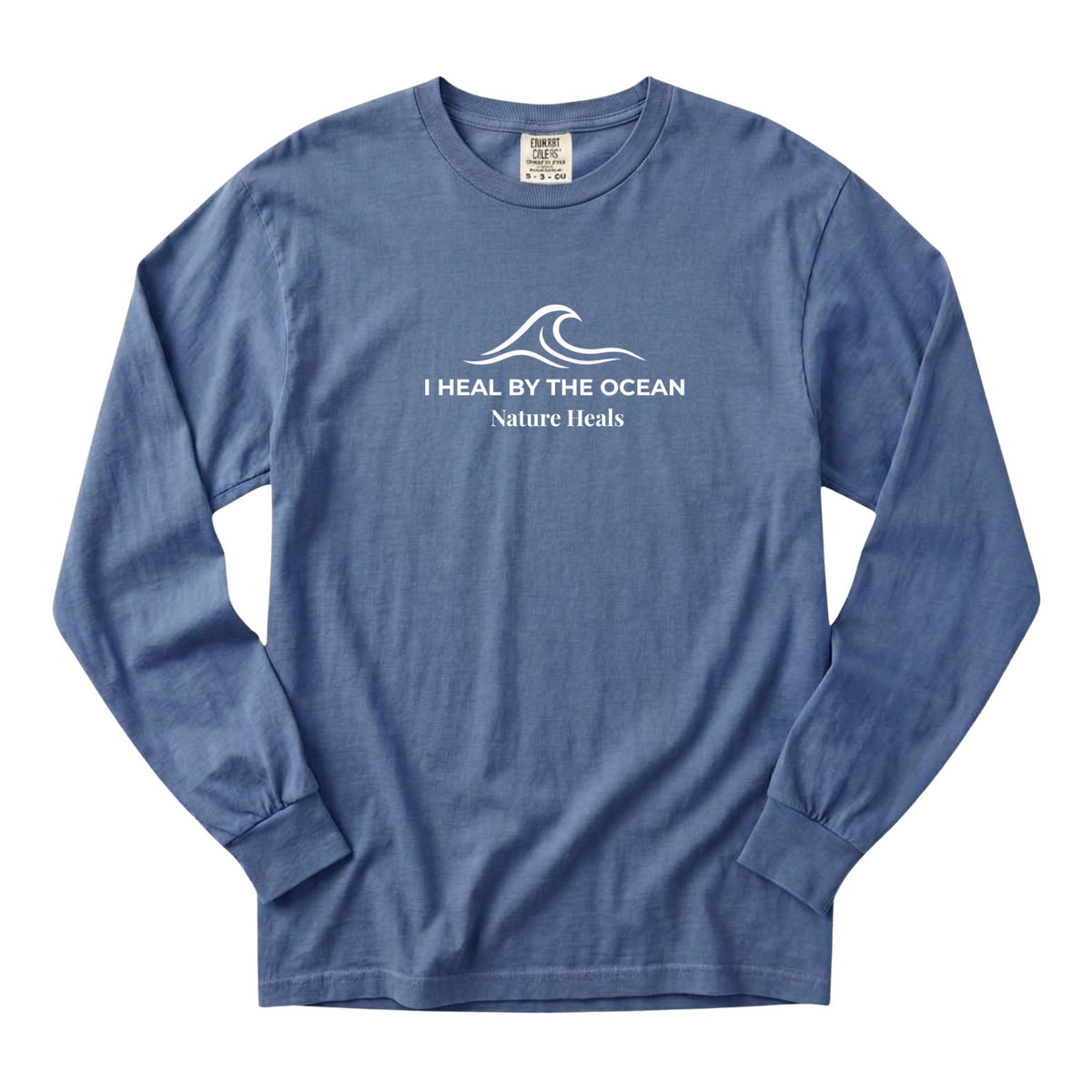 A blue long-sleeve t-shirt with a white graphic on the chest showing an ocean wave and the text 'I HEAL BY THE OCEAN  Nature Heals'.