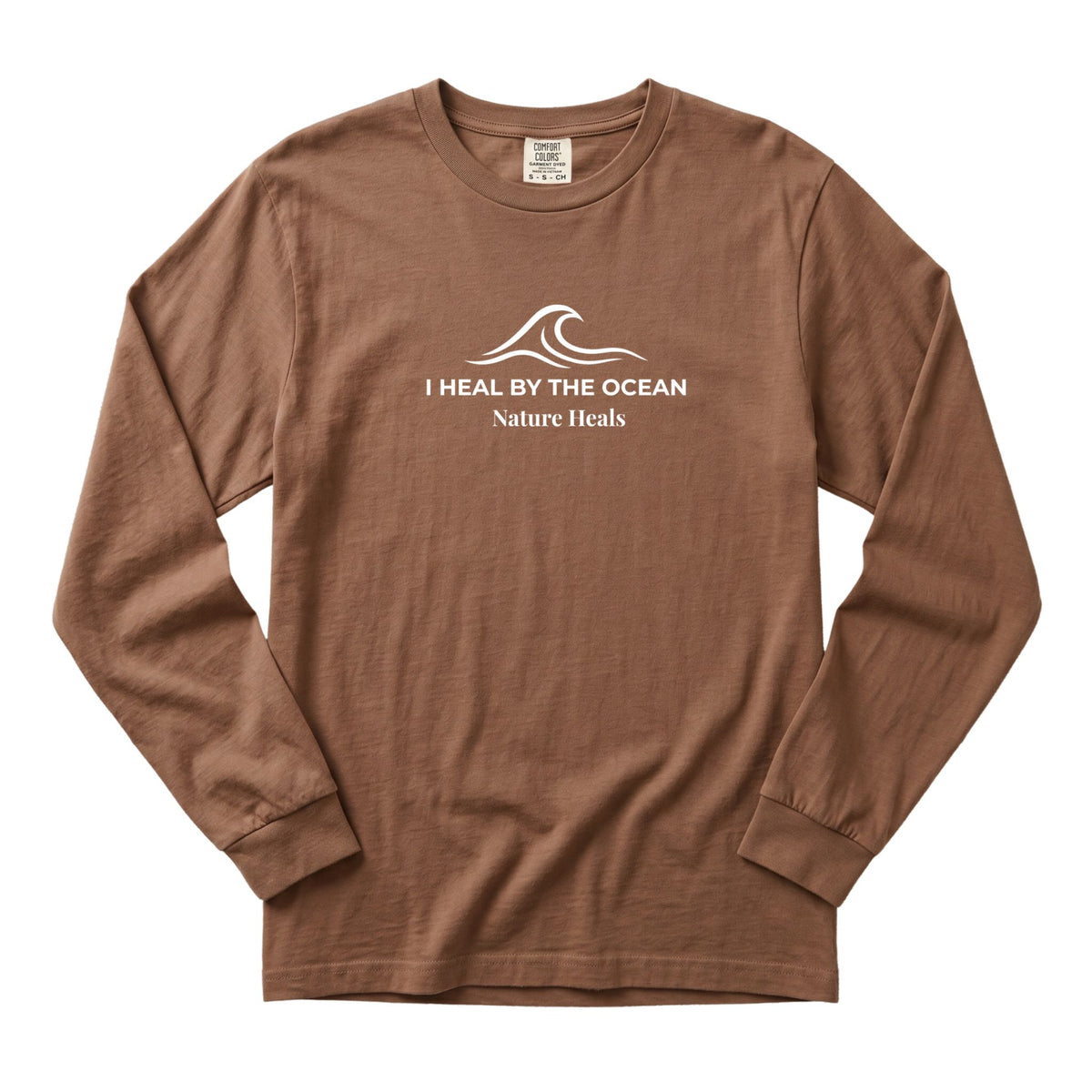 An espresso brown colored long-sleeve t-shirt with a white graphic on the chest showing an ocean wave and the text 'I HEAL BY THE OCEAN  Nature Heals'.