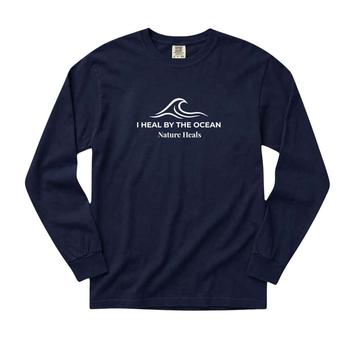 A navy-blue long-sleeve t-shirt with a white graphic on the chest showing an ocean wave and the text 'I HEAL BY THE OCEAN  Nature Heals'.