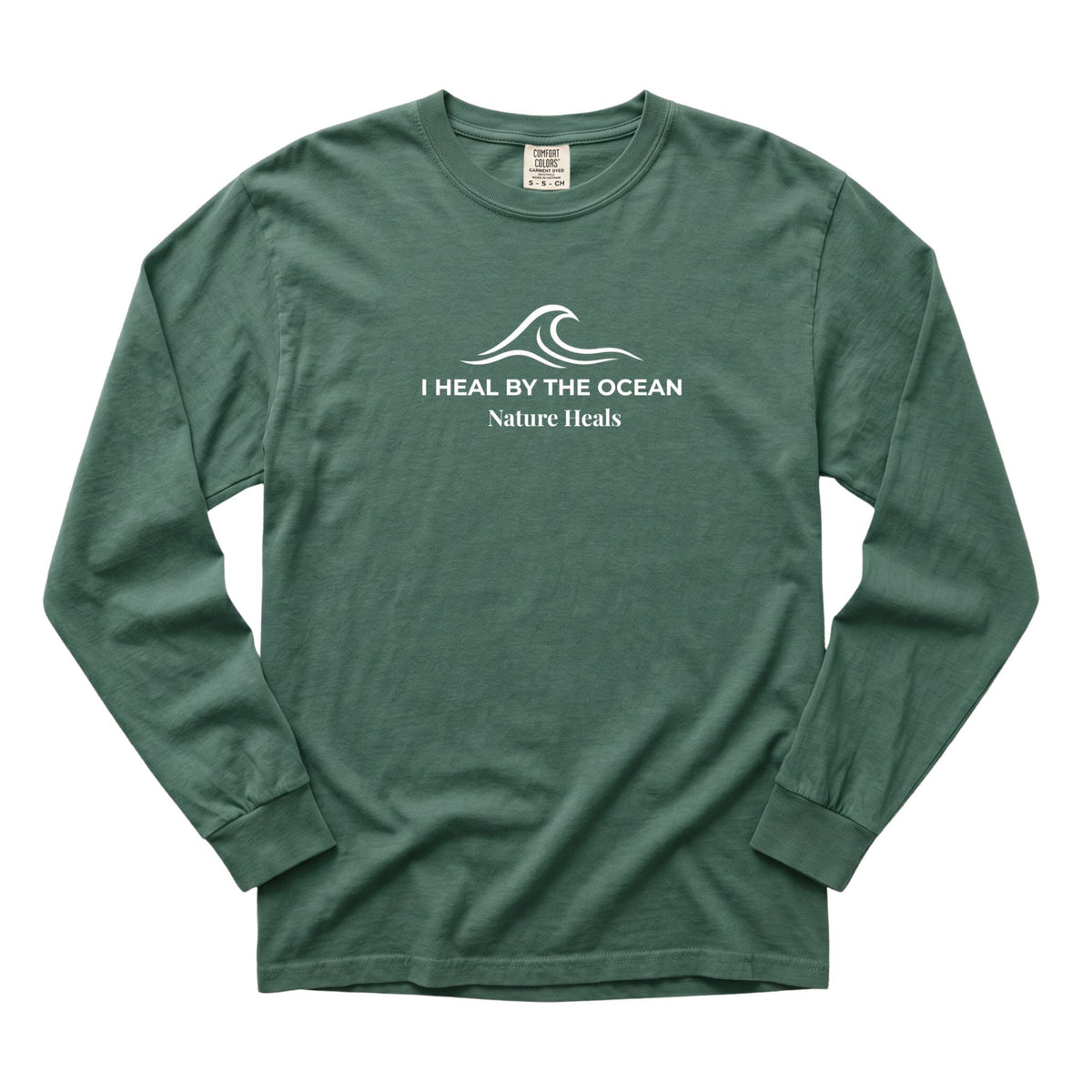 A blue-spruce  colored long-sleeve t-shirt with a white graphic on the chest showing an ocean wave and the text 'I HEAL BY THE OCEAN  Nature Heals'.