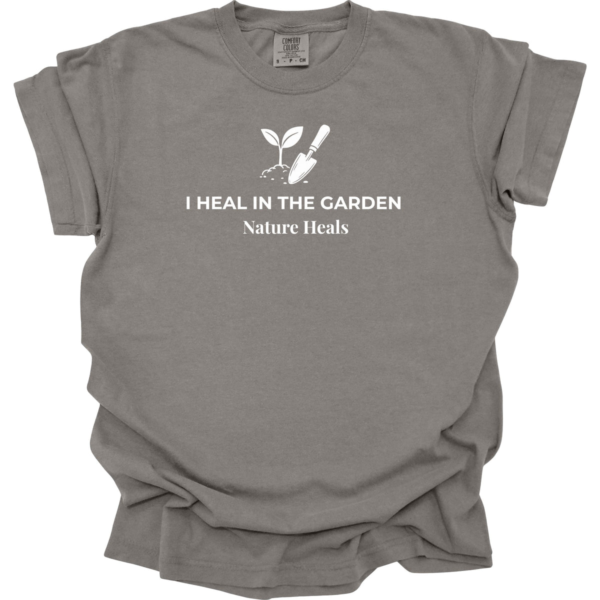 A gray short-sleeve t-shirt with a white graphic print of a sprout and trowel with the text 'I HEAL IN THE GARDEN Nature Heals' on the front, displayed against a solid white background.