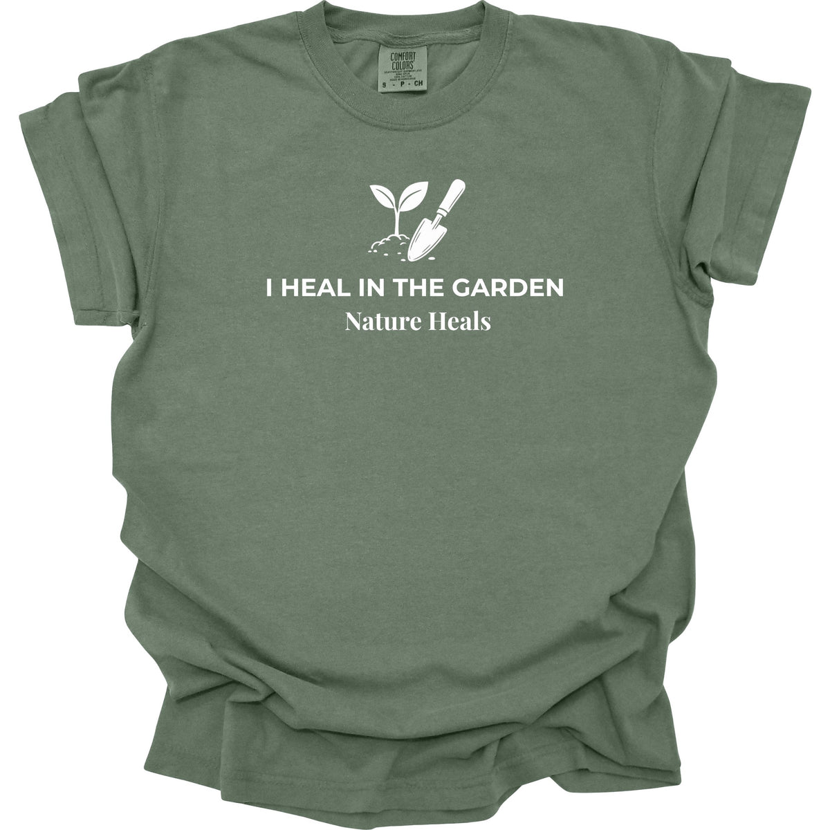 A green  short-sleeve t-shirt with a white graphic print of a sprout and trowel with the text 'I HEAL IN THE GARDEN Nature Heals' on the front, displayed against a solid white background.