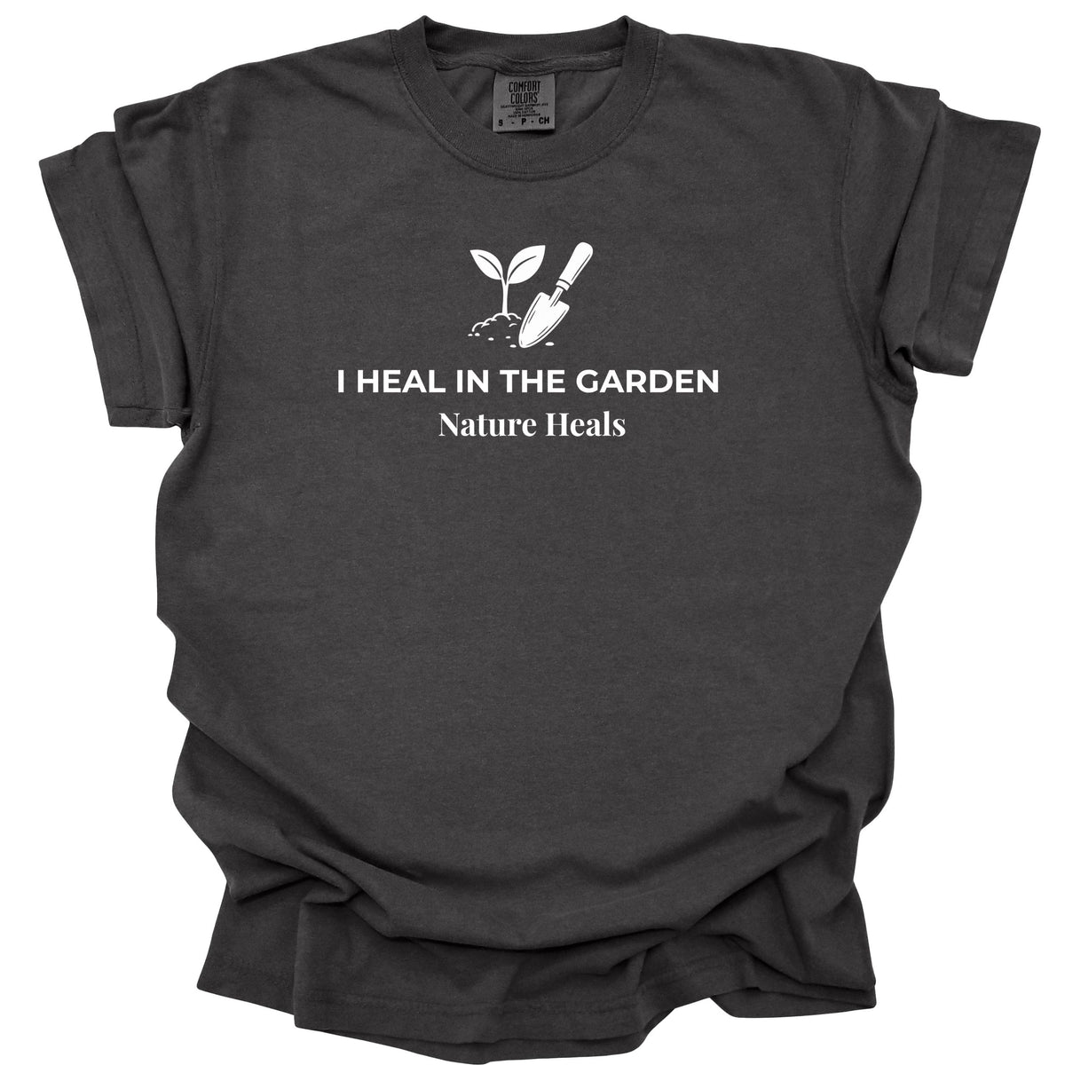 A dark charcoal gray t-shirt with a white graphic print of a sprout, trowel, and the text 'I HEAL IN THE GARDEN Nature Heals' on the chest, displayed against a plain white background.