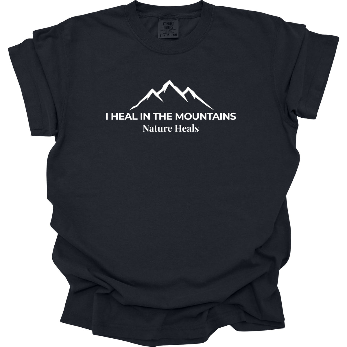 A black colored short-sleeve t-shirt with a white graphic of a mountain range and the text 'I HEAL IN THE MOUNTAINS Nature Heals' printed on the chest, displayed against a solid white background.