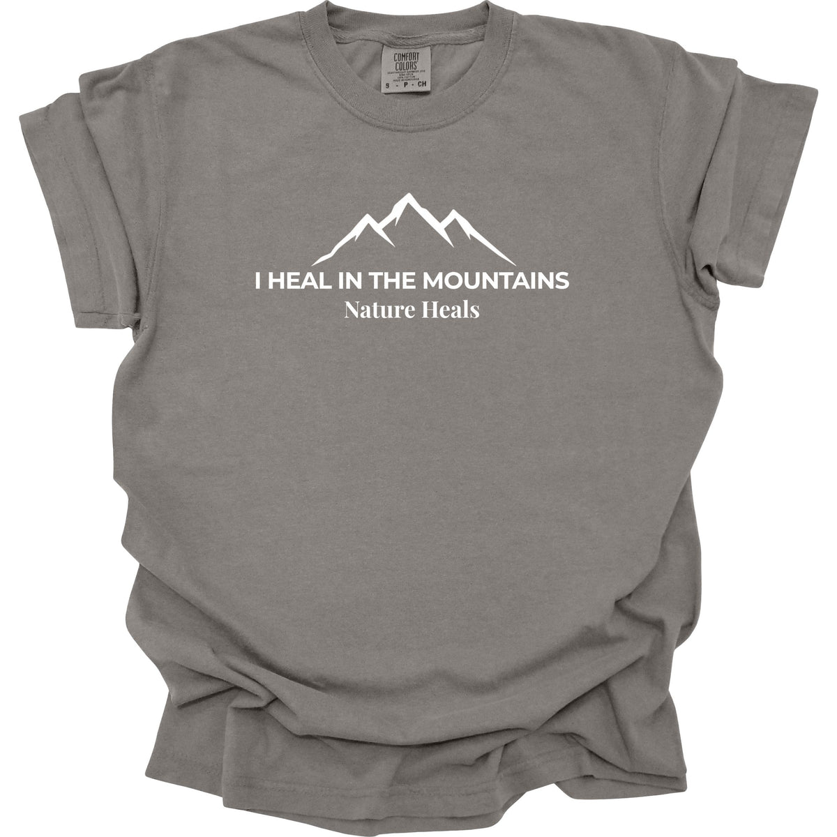 A gray colored short-sleeve t-shirt with a white graphic of a mountain range and the text 'I HEAL IN THE MOUNTAINS Nature Heals' printed on the chest, displayed against a solid white background.