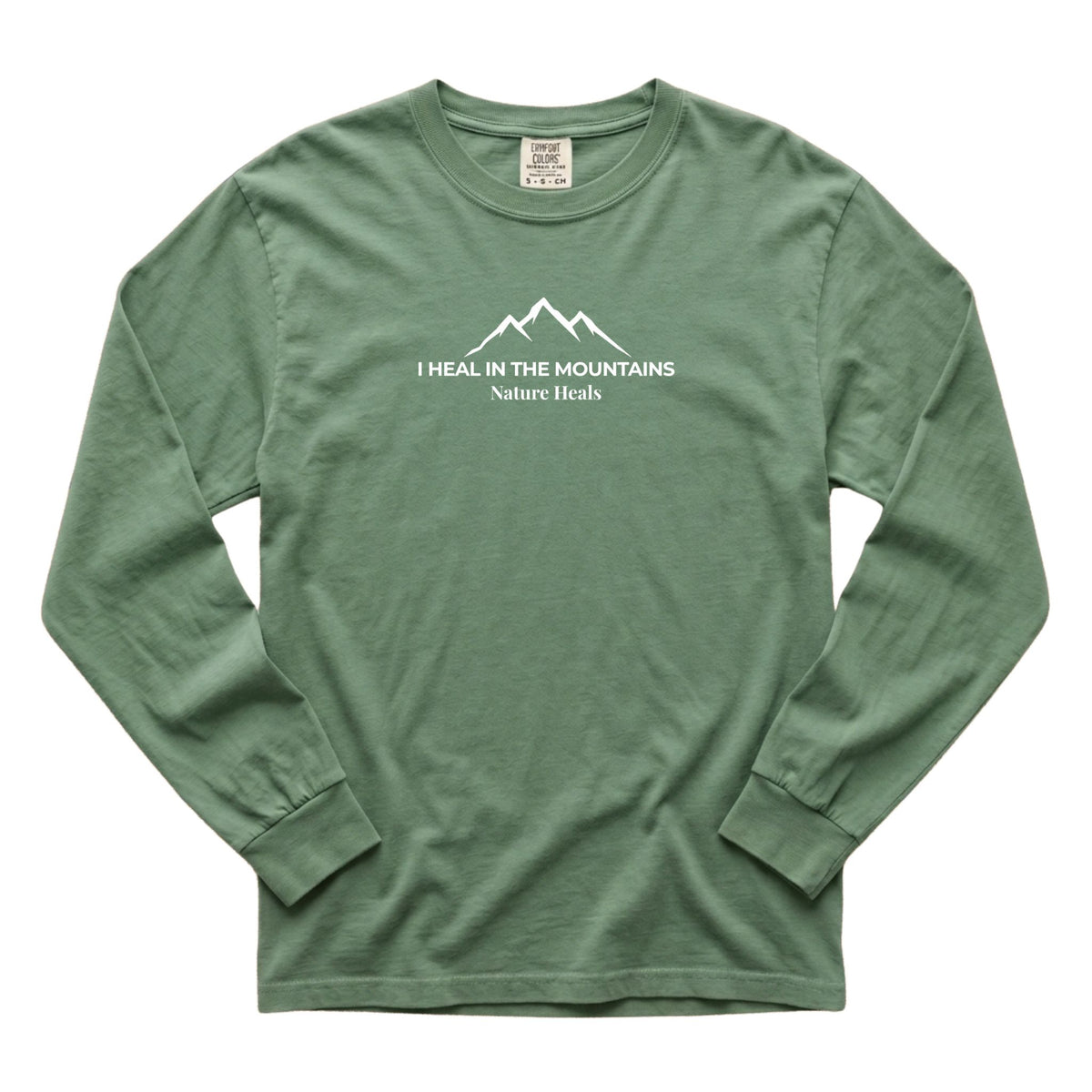 A light green long-sleeve t-shirt with a white graphic on the chest showing a mountain range and the text 'I HEAL IN THE MOUNTAINS Nature Heals'.