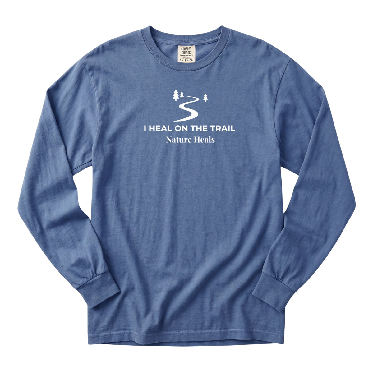 A blue long-sleeve t-shirt with a white graphic print on the chest showing a winding trail with a couple of trees and the text 'I HEAL ON THE TRAIL Nature Heals'.
