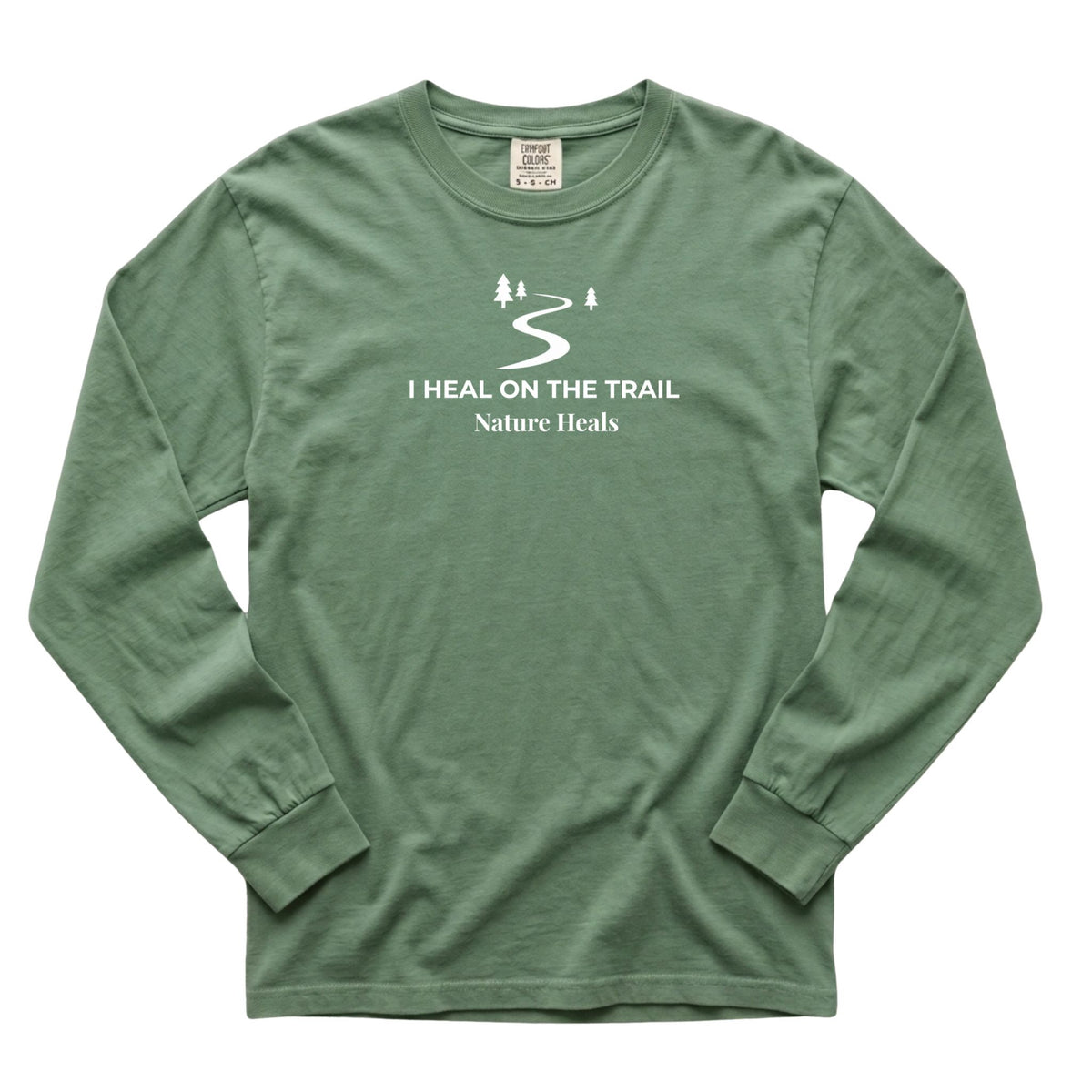 A light green long-sleeve t-shirt with a white graphic print on the chest that reads 'I HEAL ON THE TRAIL Nature Heals' with a trail and trees icon, shown on a plain white background.