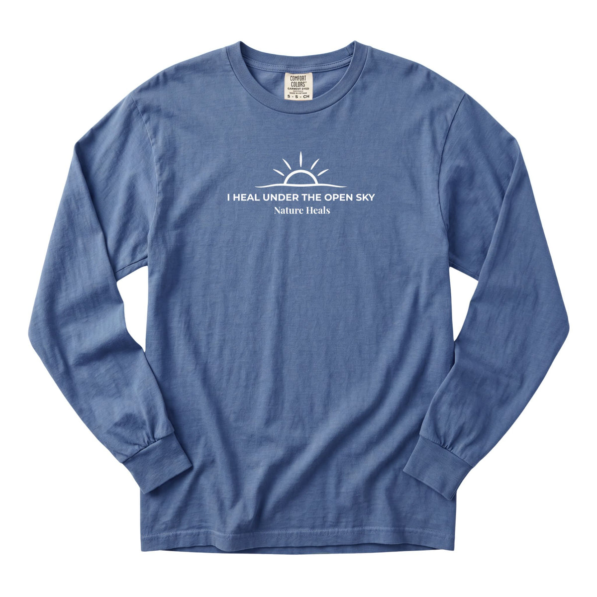 A blue long-sleeve crewneck t-shirt with a white graphic print of a rising sun and the text 'I HEAL UNDER THE OPEN SKY Nature Heals' on the chest, displayed flat against a white background.