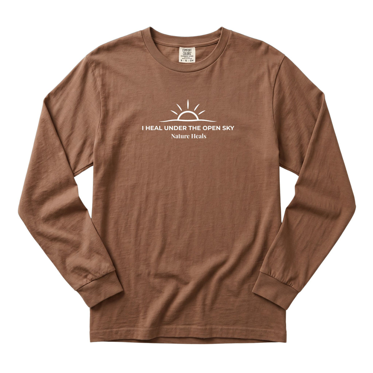 A brown long-sleeve crewneck t-shirt with a white graphic on the chest showing a sun and the text 'I HEAL UNDER THE OPEN SKY Nature Heals'.
