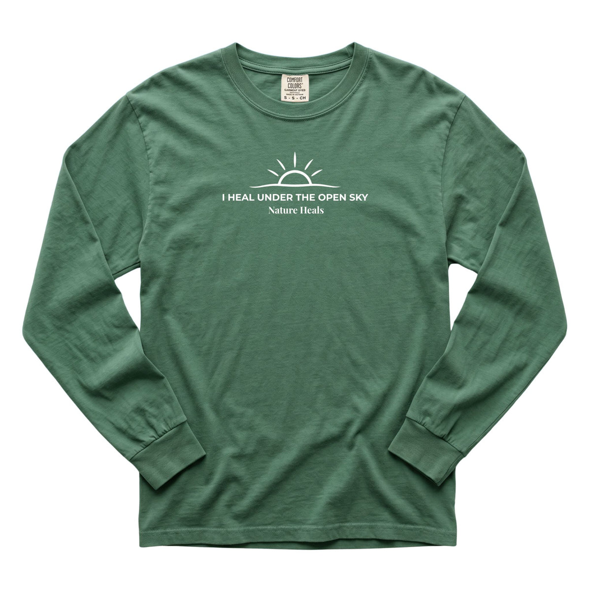 A green long-sleeve t-shirt with a white graphic print on the chest that reads 'I HEAL UNDER THE OPEN SKY' and 'Nature Heals' below it, displayed flat against a white background.