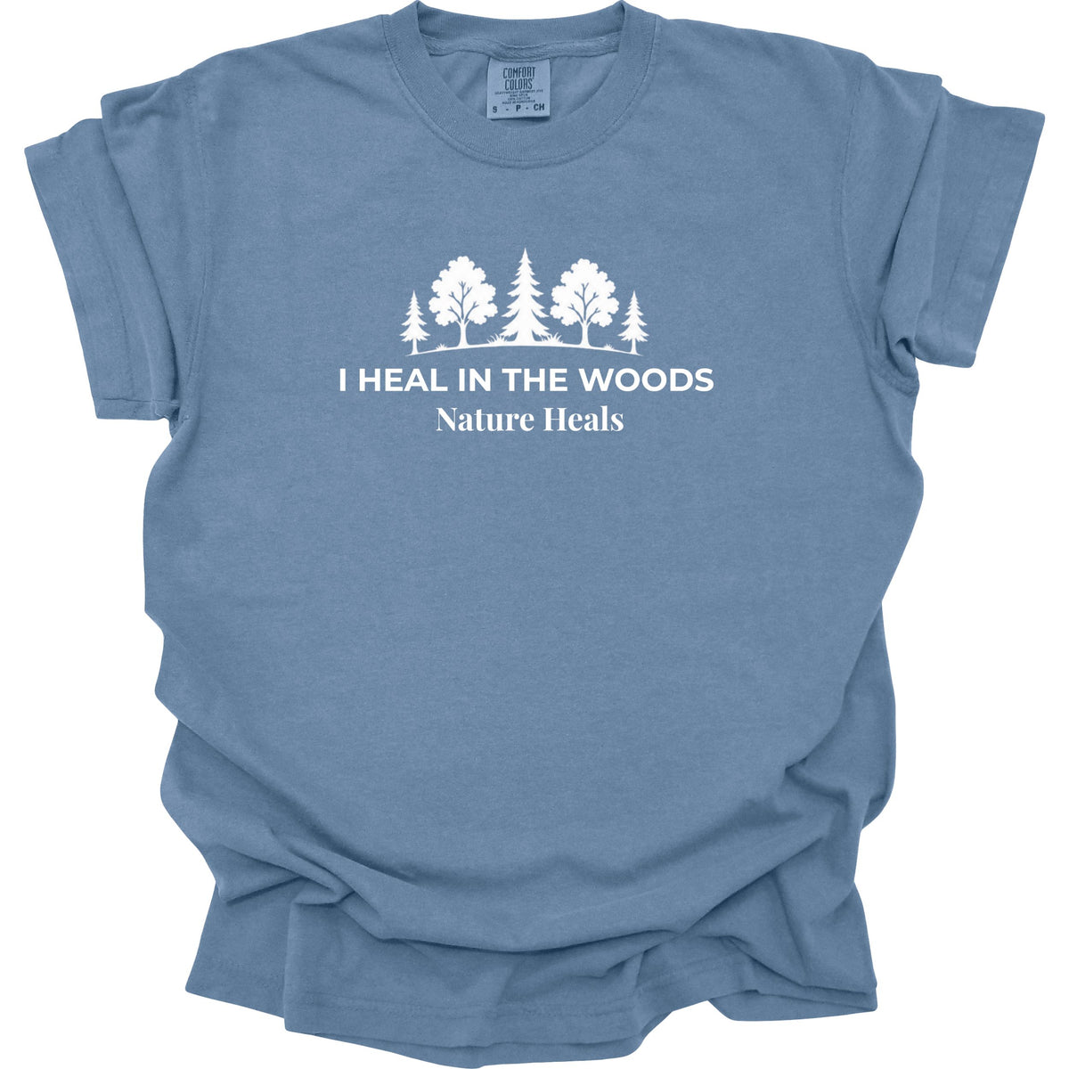 A  blue crewneck t-shirt with a white graphic of trees and the text 'I HEAL IN THE WOODS Nature Heals' printed on the chest, displayed on a clean white background.
