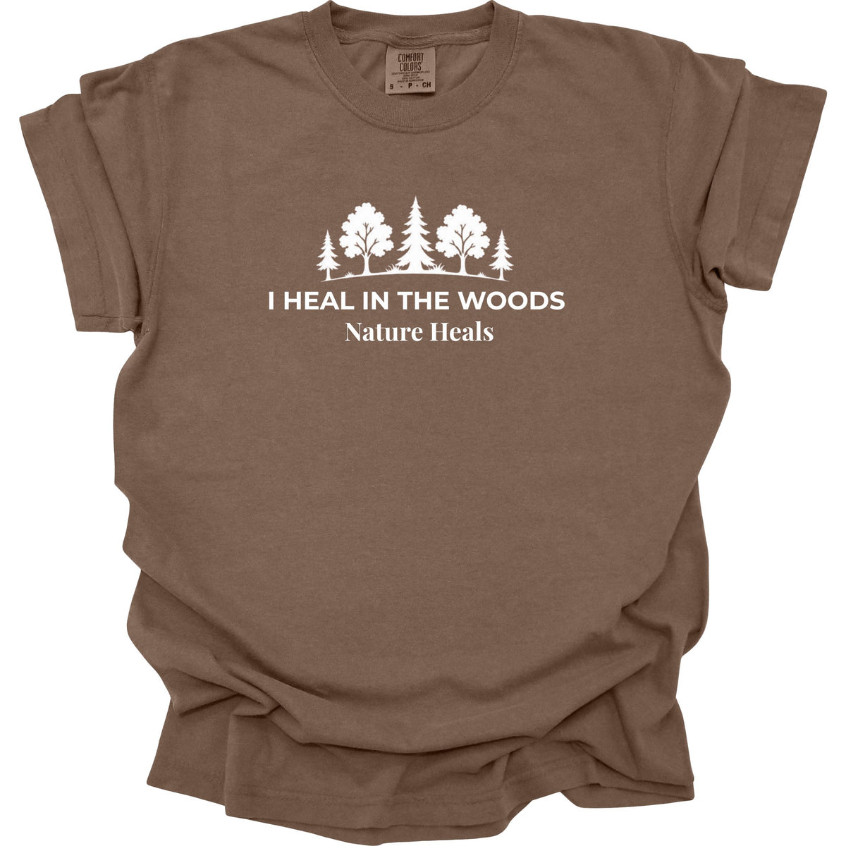 A brown short-sleeve t-shirt with a white graphic of trees and the text 'I HEAL IN THE WOODS Nature Heals' printed on the chest, displayed on a clean white background.