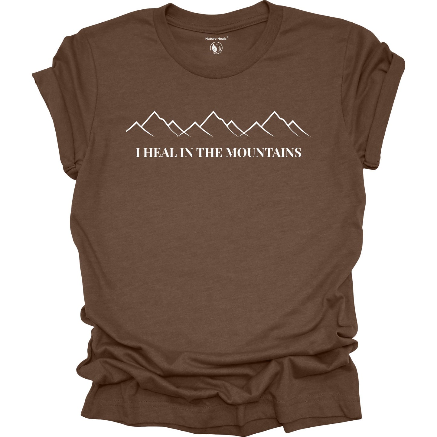 Brown t-shirt with mountain graphic and text 'I Heal in the Mountains' on a white background