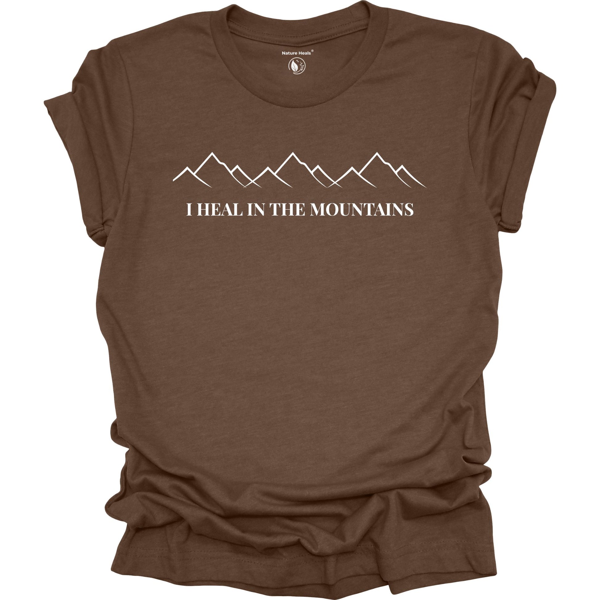 Brown t-shirt with mountain graphic and text 'I Heal in the Mountains' on a white background