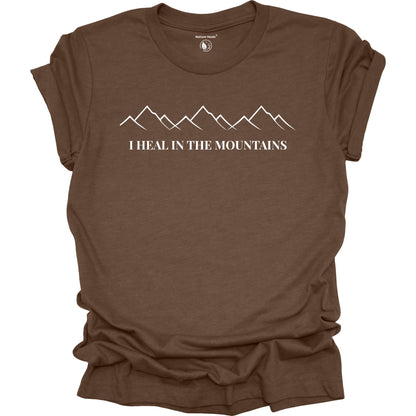 Brown t-shirt with mountain graphic and text 'I Heal in the Mountains' on a white background