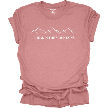 Mauve t-shirt with mountain graphic and text 'I Heal in the Mountains' on a white background
