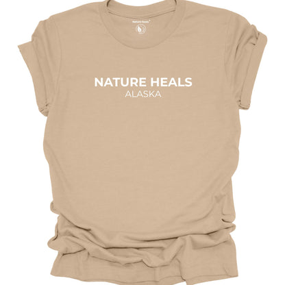 Tan t-shirt with text 'Nature Heals and Alaska' on a white background