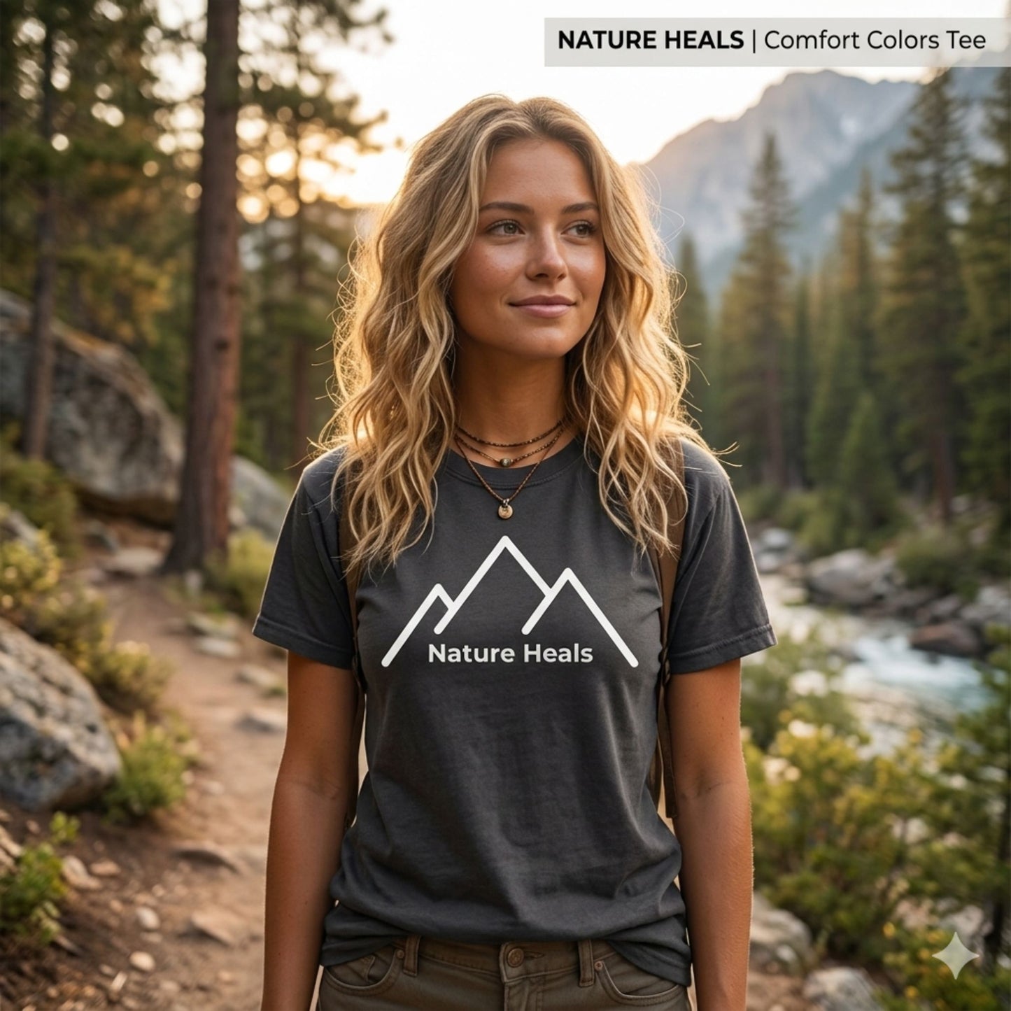 Woman wearing a 'Nature Heals' t-shirt with white mountain graphic in a forest setting