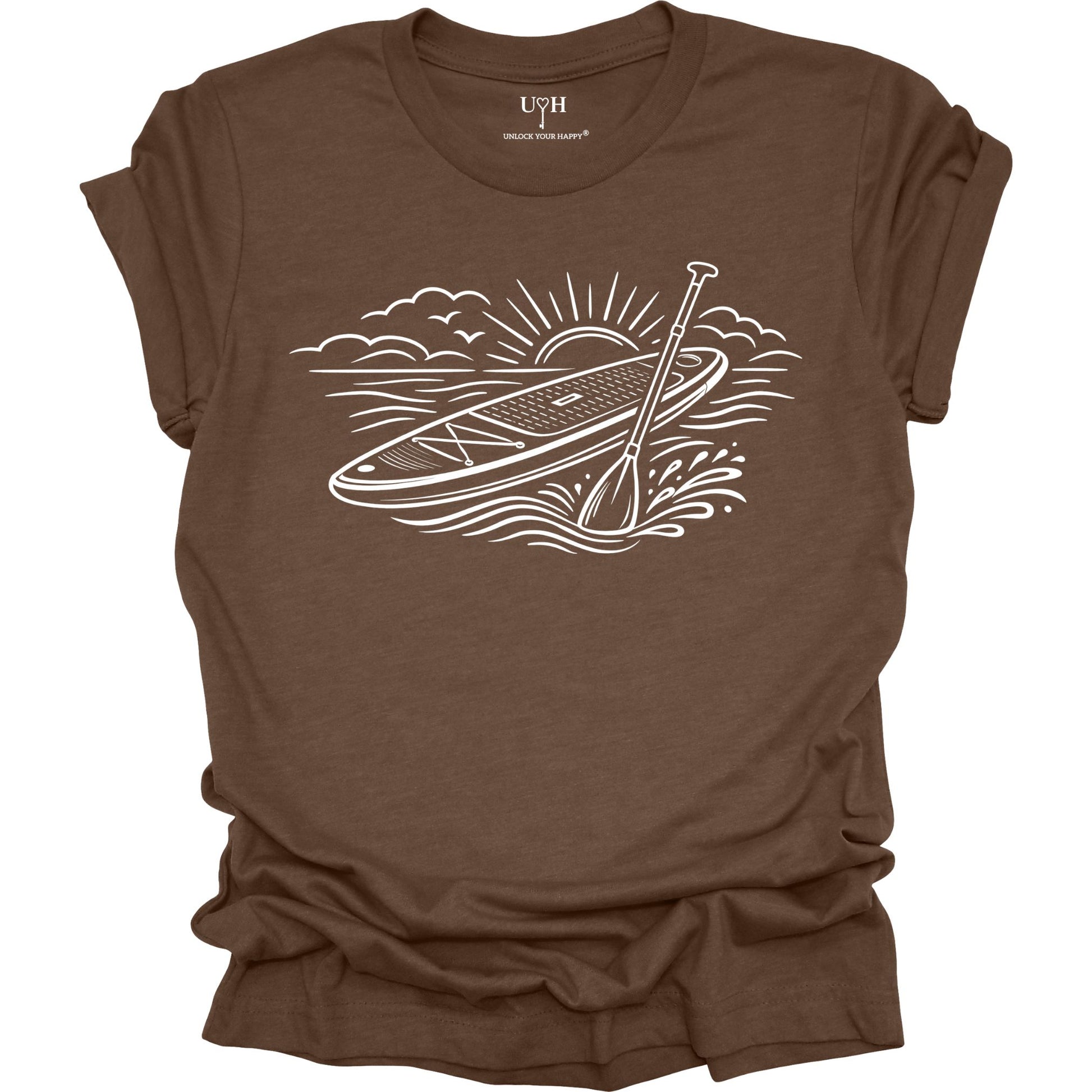 Brown t-shirt featuring white line art of a stand up paddle board with paddle on water at sunrise, worn by model, ocean and beach lifestyle design