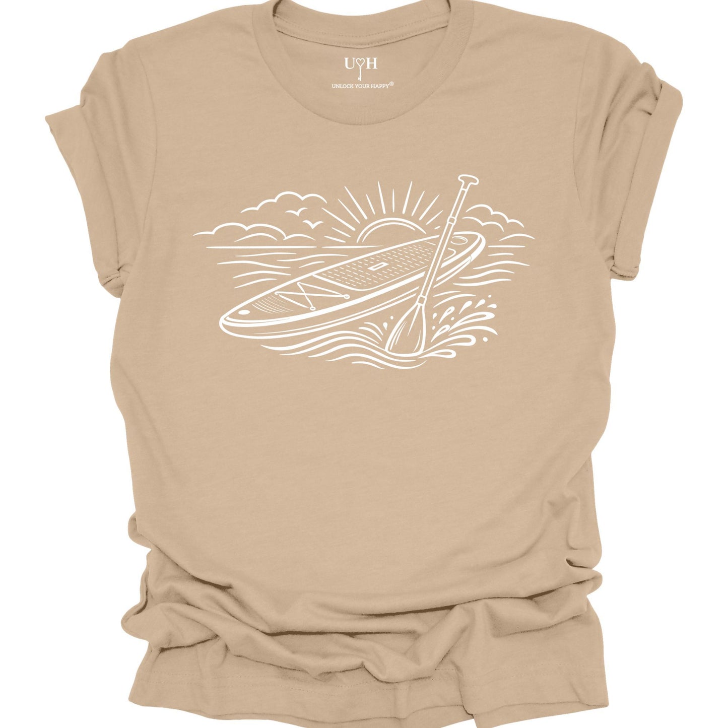 Tan t-shirt featuring white line art of a stand up paddle board with paddle on water at sunrise, worn by model, ocean and beach lifestyle design
