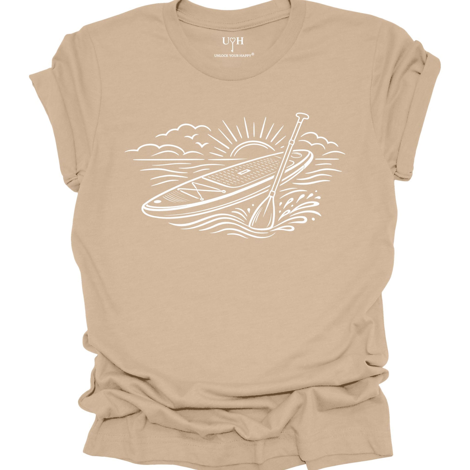 Tan t-shirt featuring white line art of a stand up paddle board with paddle on water at sunrise, worn by model, ocean and beach lifestyle design