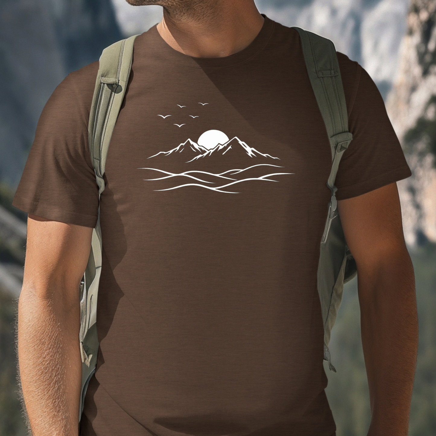 Person wearing a brown t-shirt with a mountain design in a natural setting