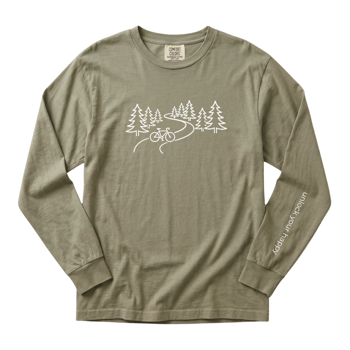 A long-sleeve crewneck t-shirt in a sandstone color, featuring a white line art graphic of pine trees, a winding road, and a bicycle on the chest, with 'Unlock Your Happy' printed vertically in white on the left sleeve.