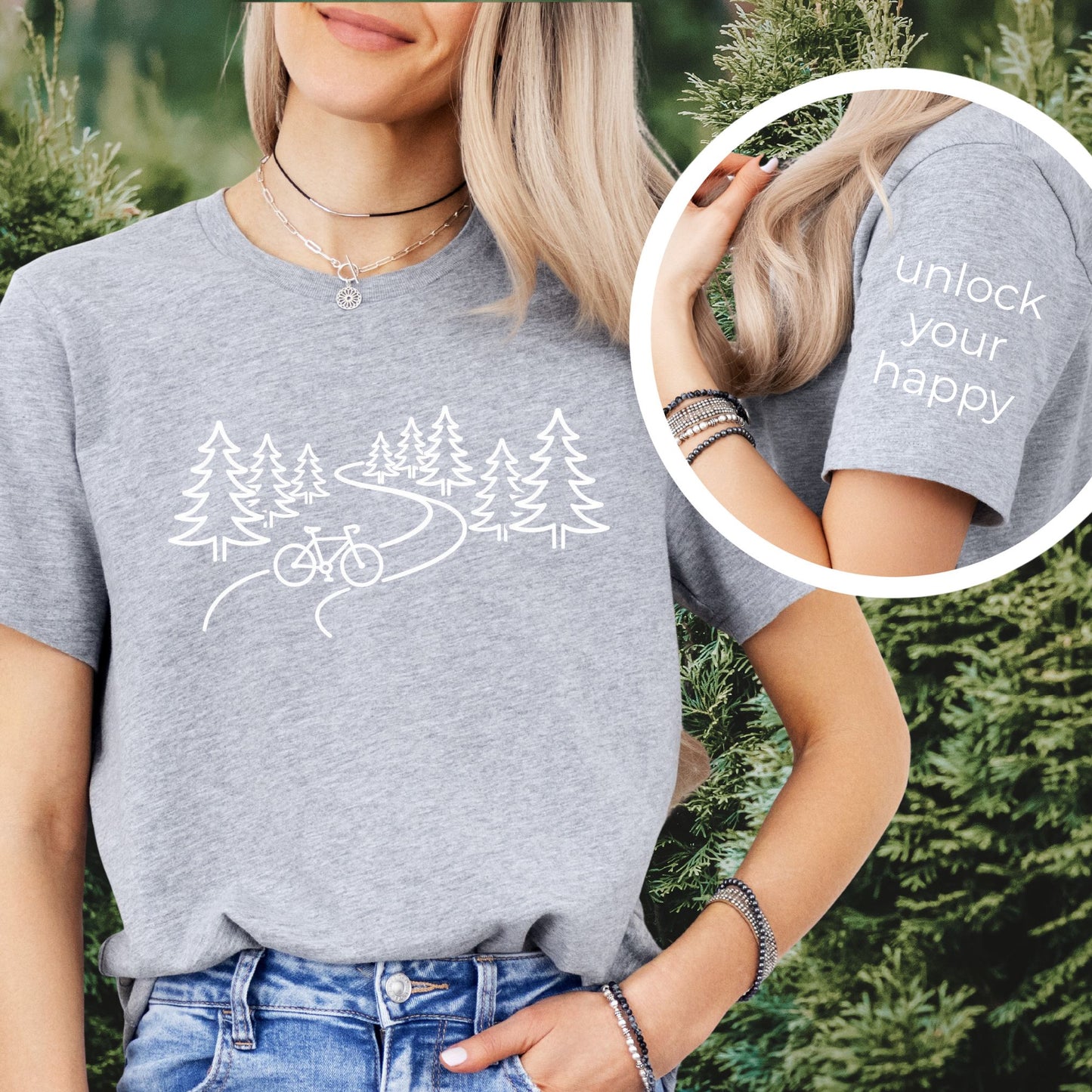 nature biking graphic gray t-shirt with minimalist forest trail and bicycle design, featuring “unlock your happy” text on sleeve on female outdoors