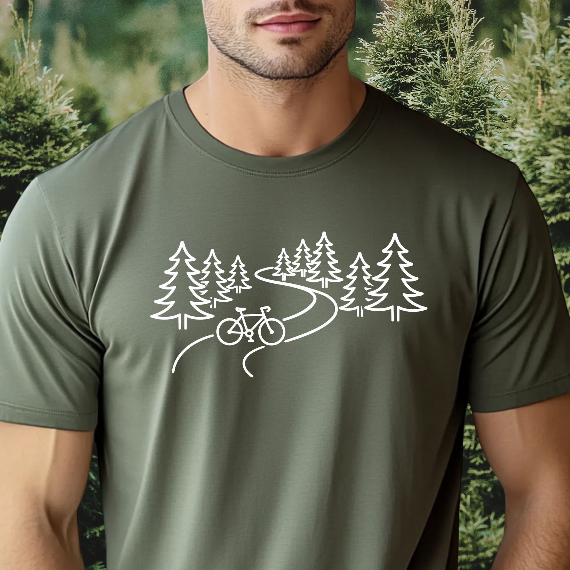 Man wearing a green t-shirt with a bicycle and trees design, standing in front of a forest.