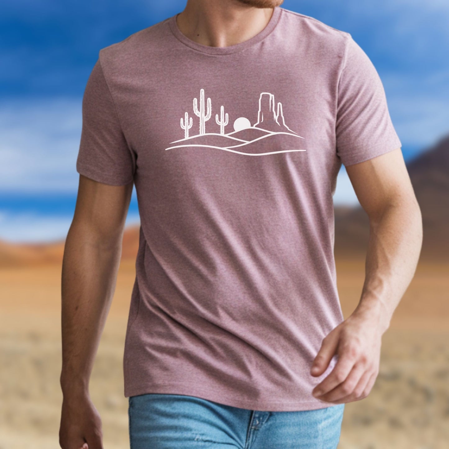 Man wearing a heather mauve desert graphic t-shirt featuring a white line art illustration of cacti and mesas. Minimalist nature-inspired apparel for mental well-being.