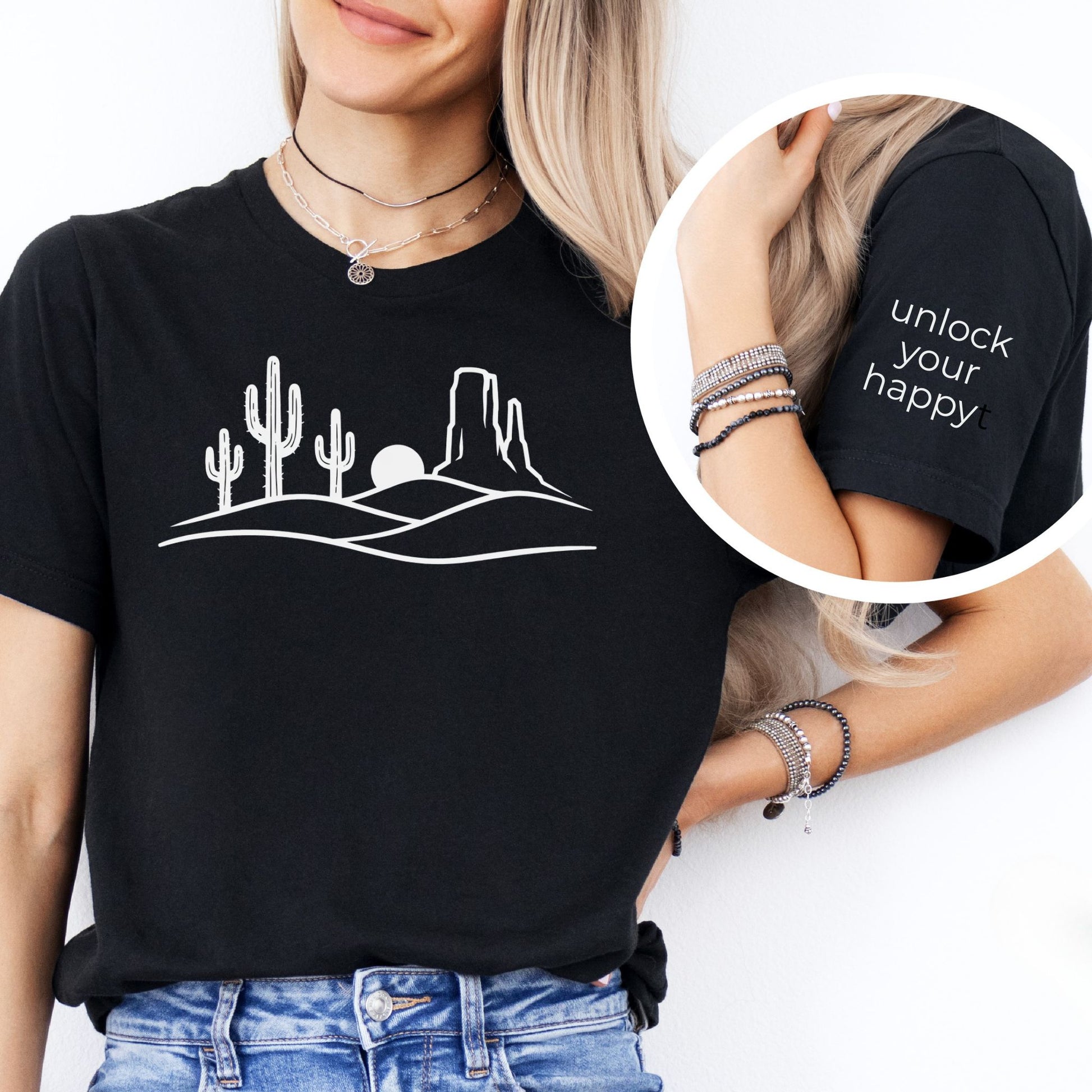 Person wearing a black desert inspired t-shirt sleeve featuring “unlock your happy” text detail