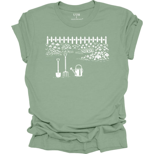 White gardening graphic on a sage t-shirt featuring garden tools and flower garden illustration with nature-inspired design 