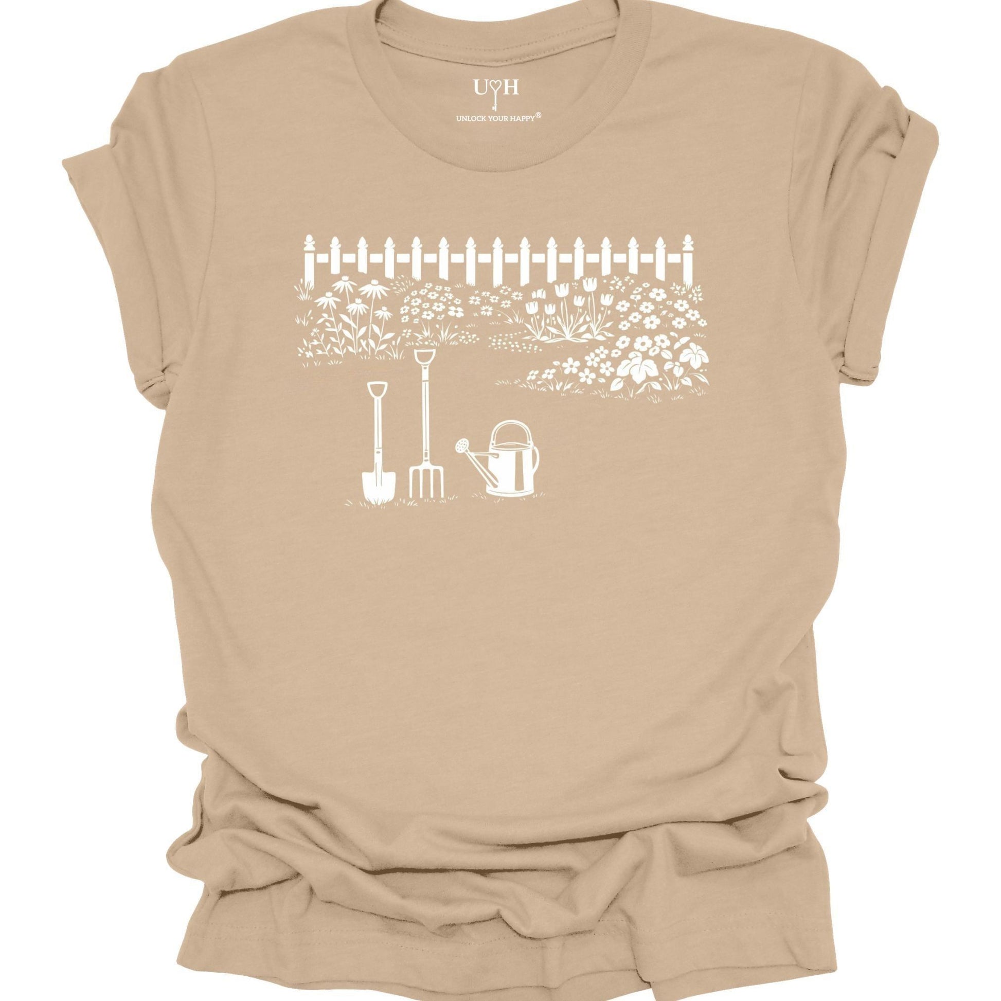 White gardening graphic on a tan t-shirt featuring garden tools and flower garden illustration with nature-inspired design 