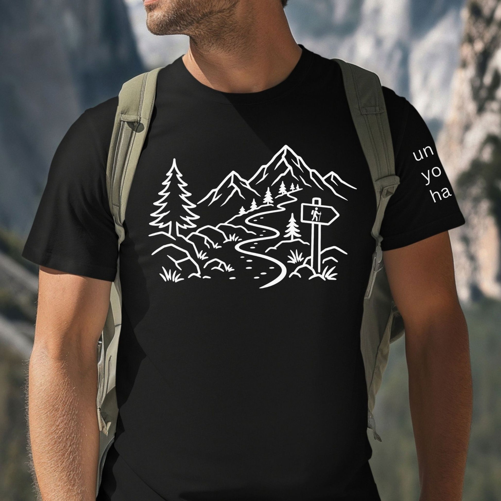 Person wearing a minimalist black t-shirt with white mountain and forest trail design, hiking path graphic for nature lovers and outdoor enthusiasts