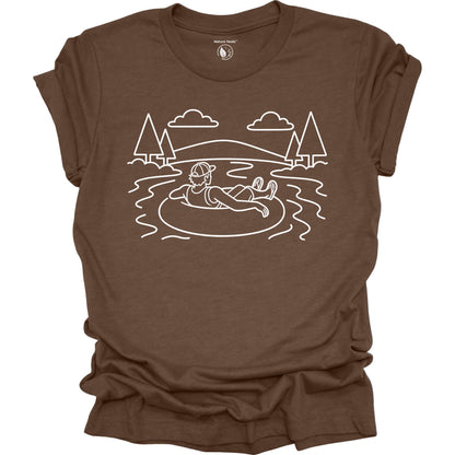 Brown t-shirt with white graphic of a person on an inner tube in a lake, surrounded by trees and mountains.