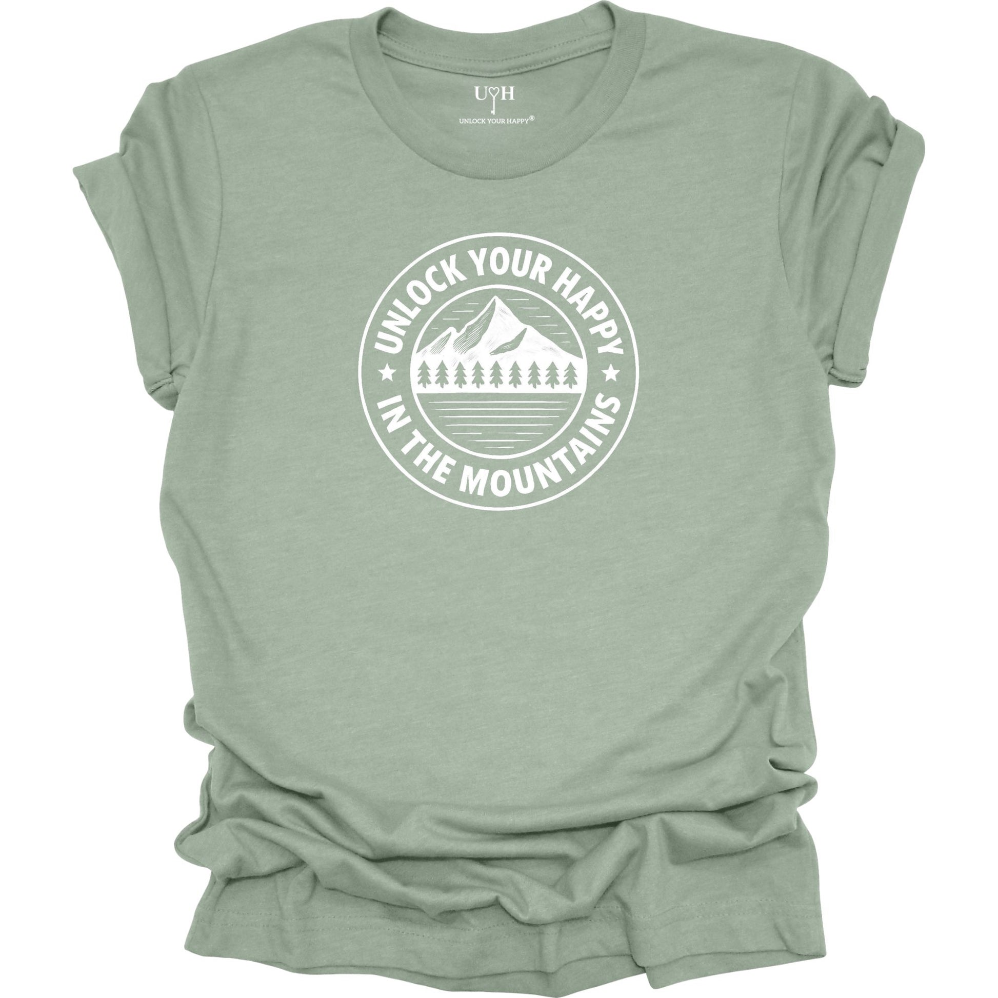 Sage unisex graphic t-shirt featuring a circular mountain and pine tree design with the text “Unlock Your Happy in the Mountains”.