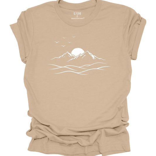 Tan t-shirt with a mountain and sunset design on a white background