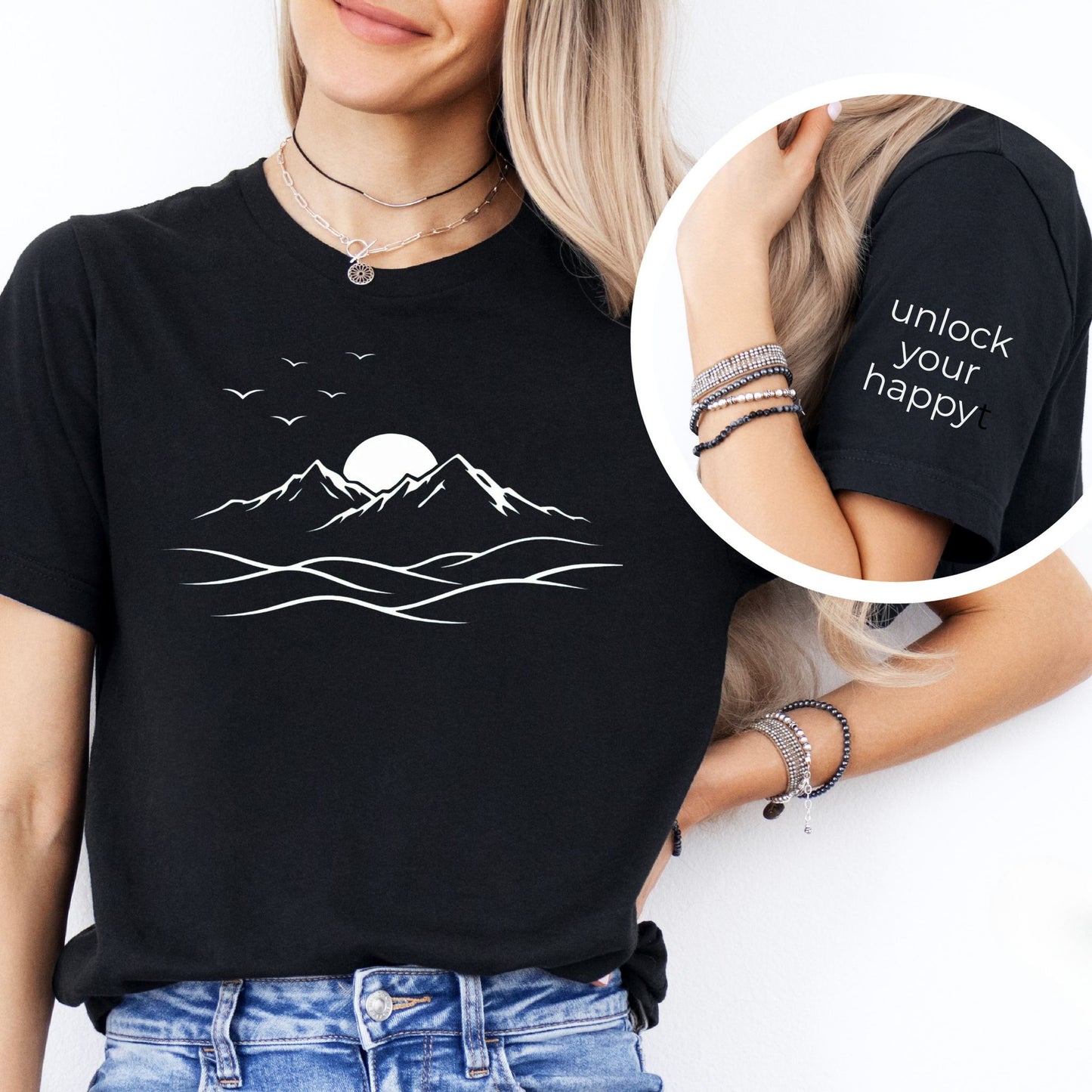 Person wearing a black t-shirt with mountain design and 'unlock your happy' text.