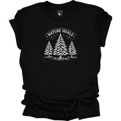 Minimalist Nature Heals t-shirt with pine tree graphic on black fabric, designed for nature lovers, wellness, and outdoor lifestyle