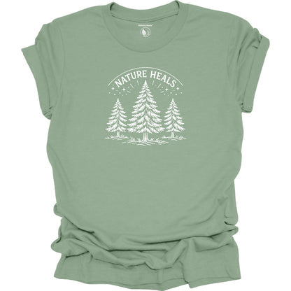 Minimalist Nature Heals t-shirt with pine tree graphic on soft sage green fabric, designed for nature lovers, wellness, and outdoor lifestyle