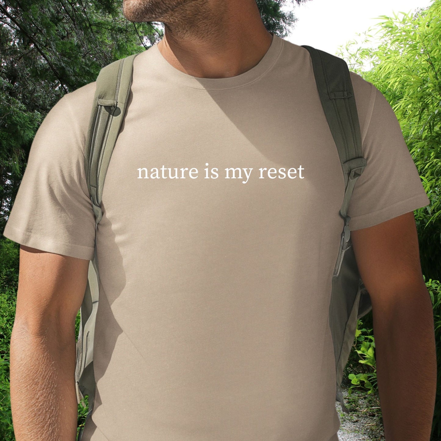 Male wearing a tan t-shirt with 'nature is my reset' text, standing outdoors with greenery.