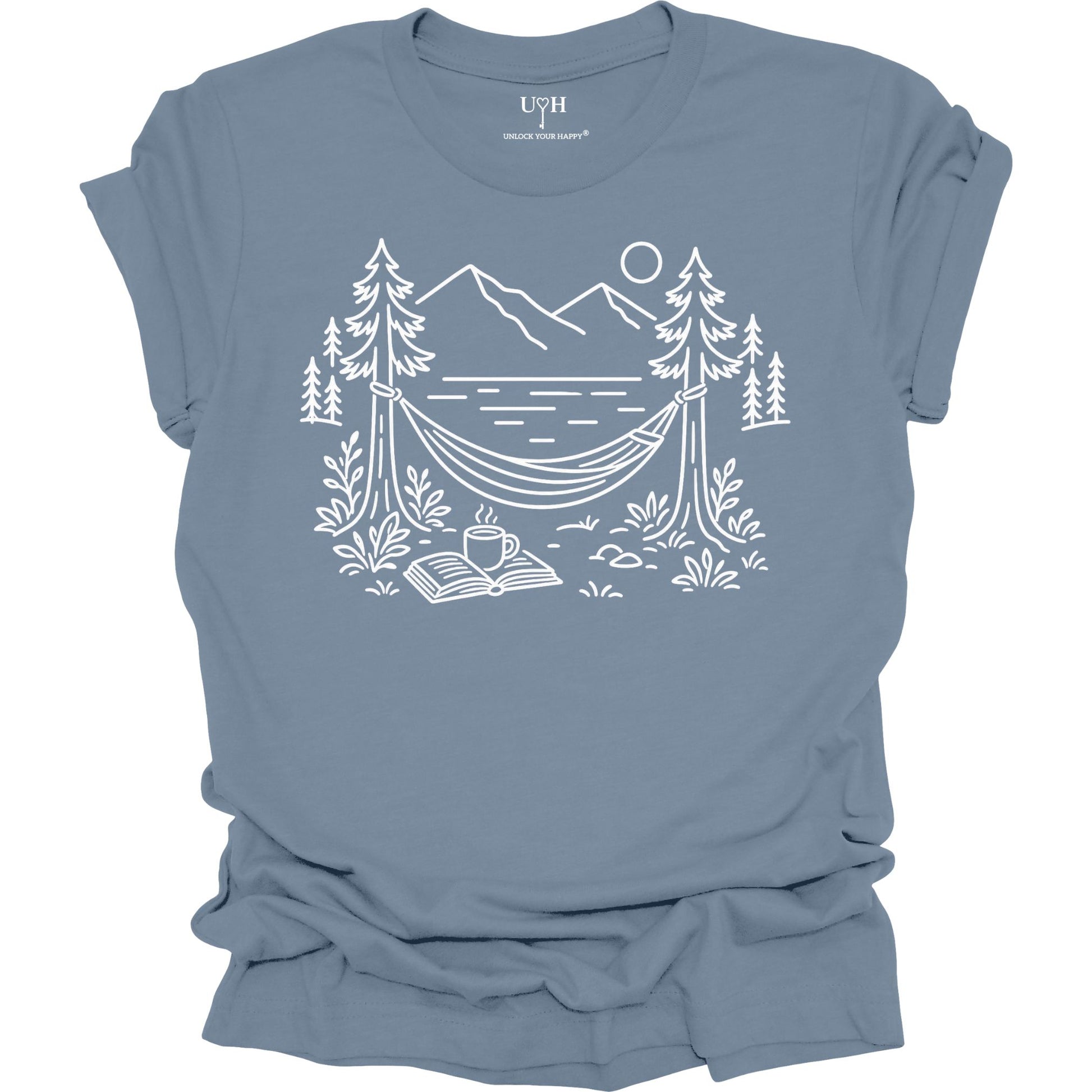 Blue unisex t-shirt with a white line art hammock scene featuring mountains, trees, a lake, coffee cup, and open book, plus ‘unlock your happy’ on the sleeve.
