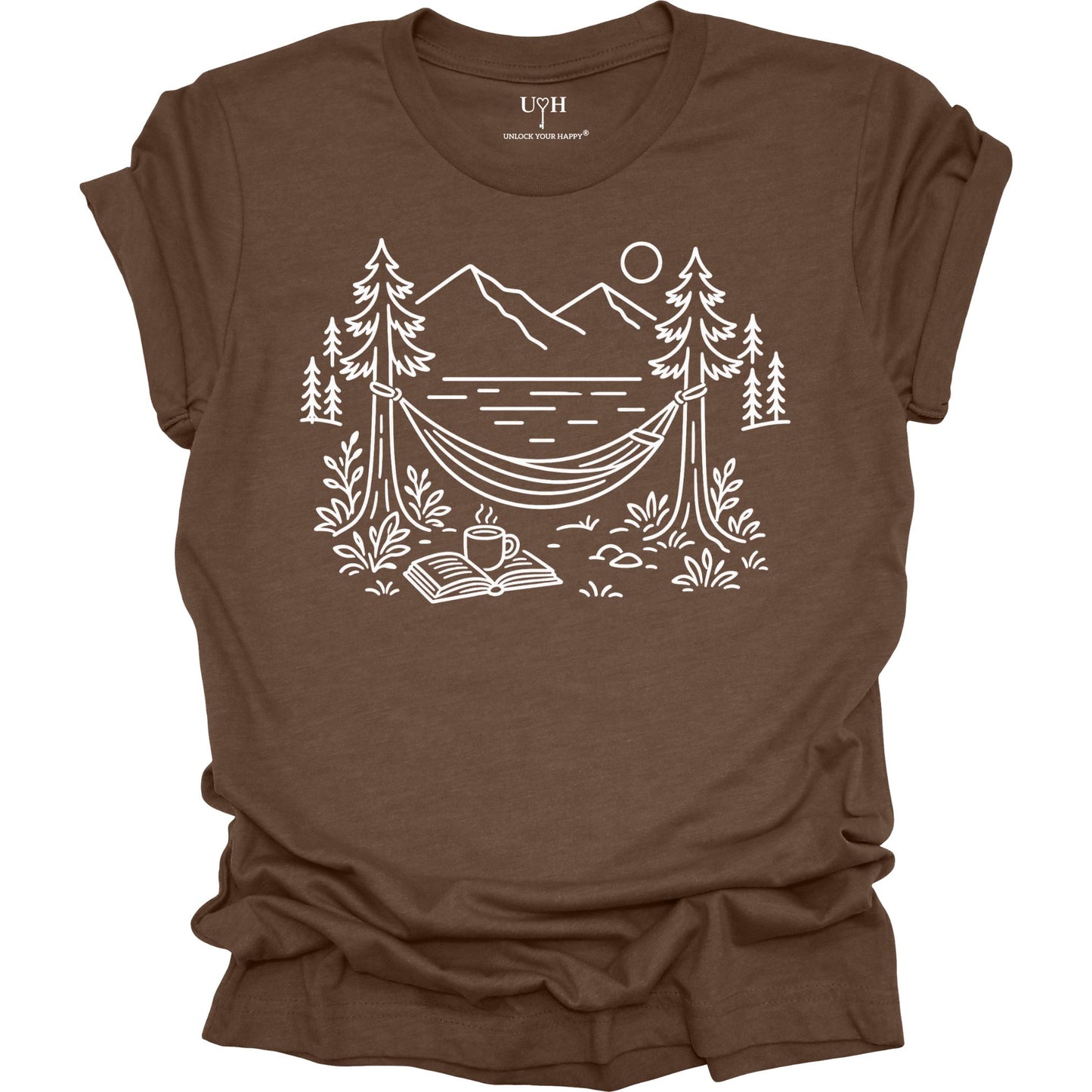 Brown unisex t-shirt with a white line art hammock scene featuring mountains, trees, a lake, coffee cup, and open book, plus ‘unlock your happy’ on the sleeve.