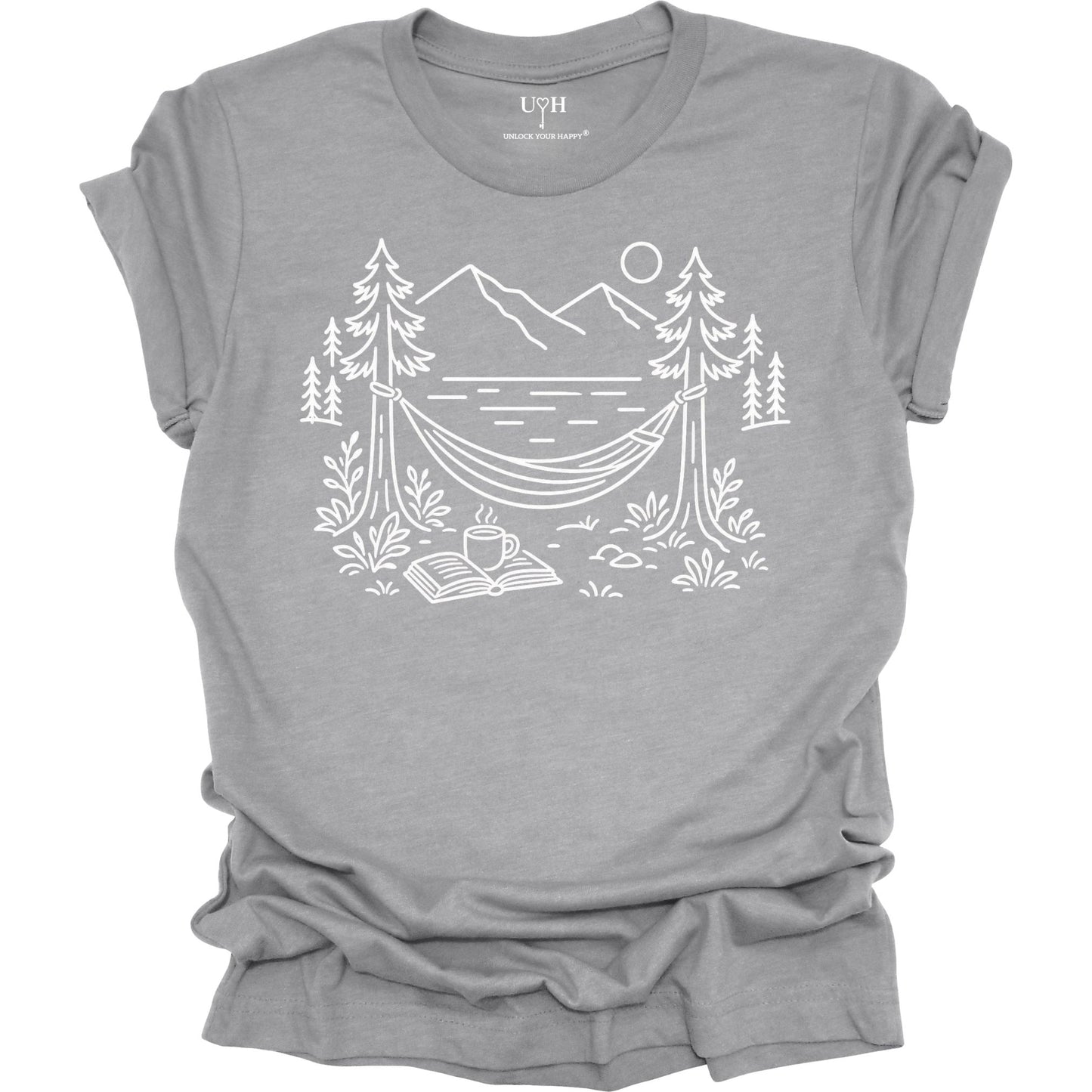 Gray unisex t-shirt with a white line art hammock scene featuring mountains, trees, a lake, coffee cup, and open book, plus ‘unlock your happy’ on the sleeve.