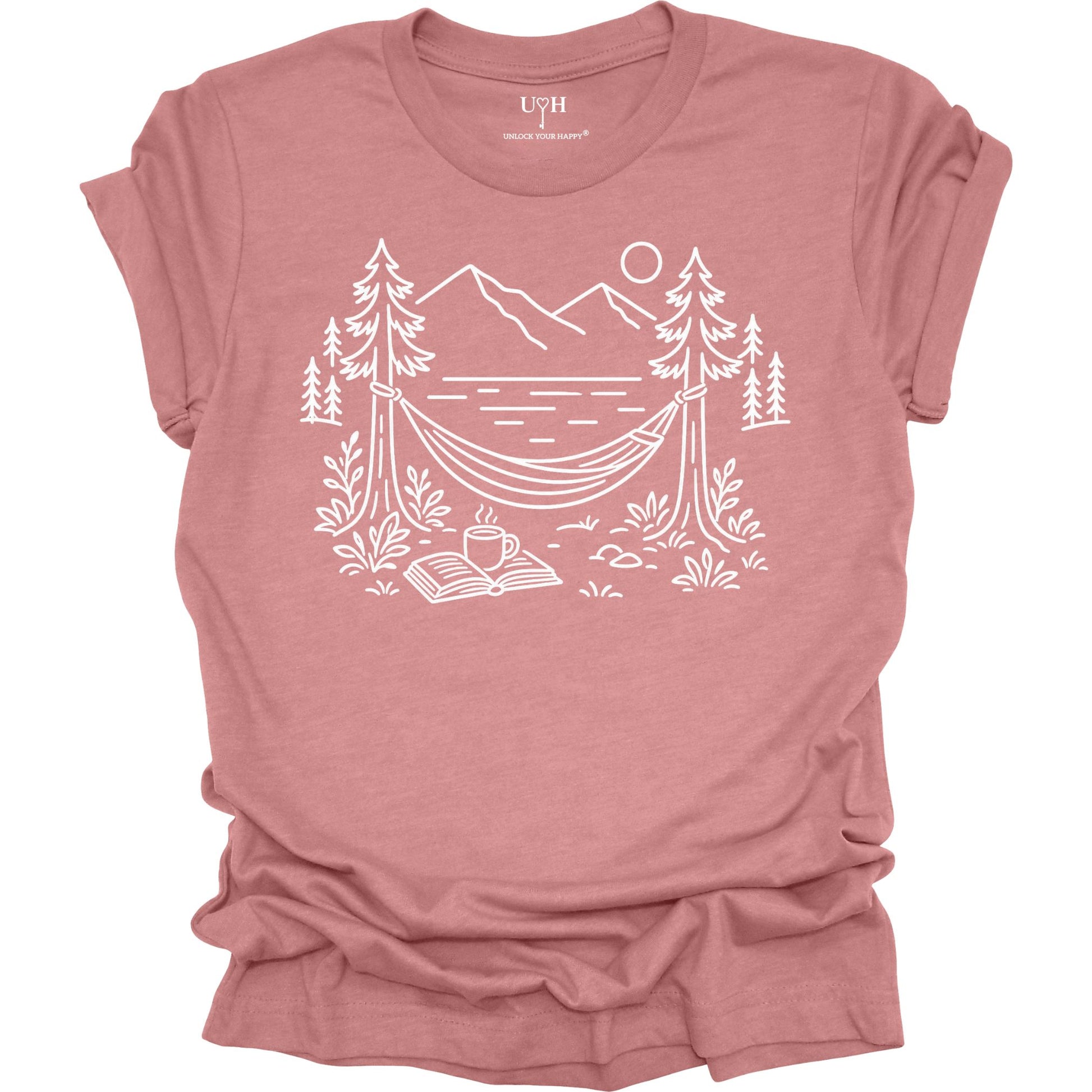 Mauve unisex t-shirt with a white line art hammock scene featuring mountains, trees, a lake, coffee cup, and open book, plus ‘unlock your happy’ on the sleeve.