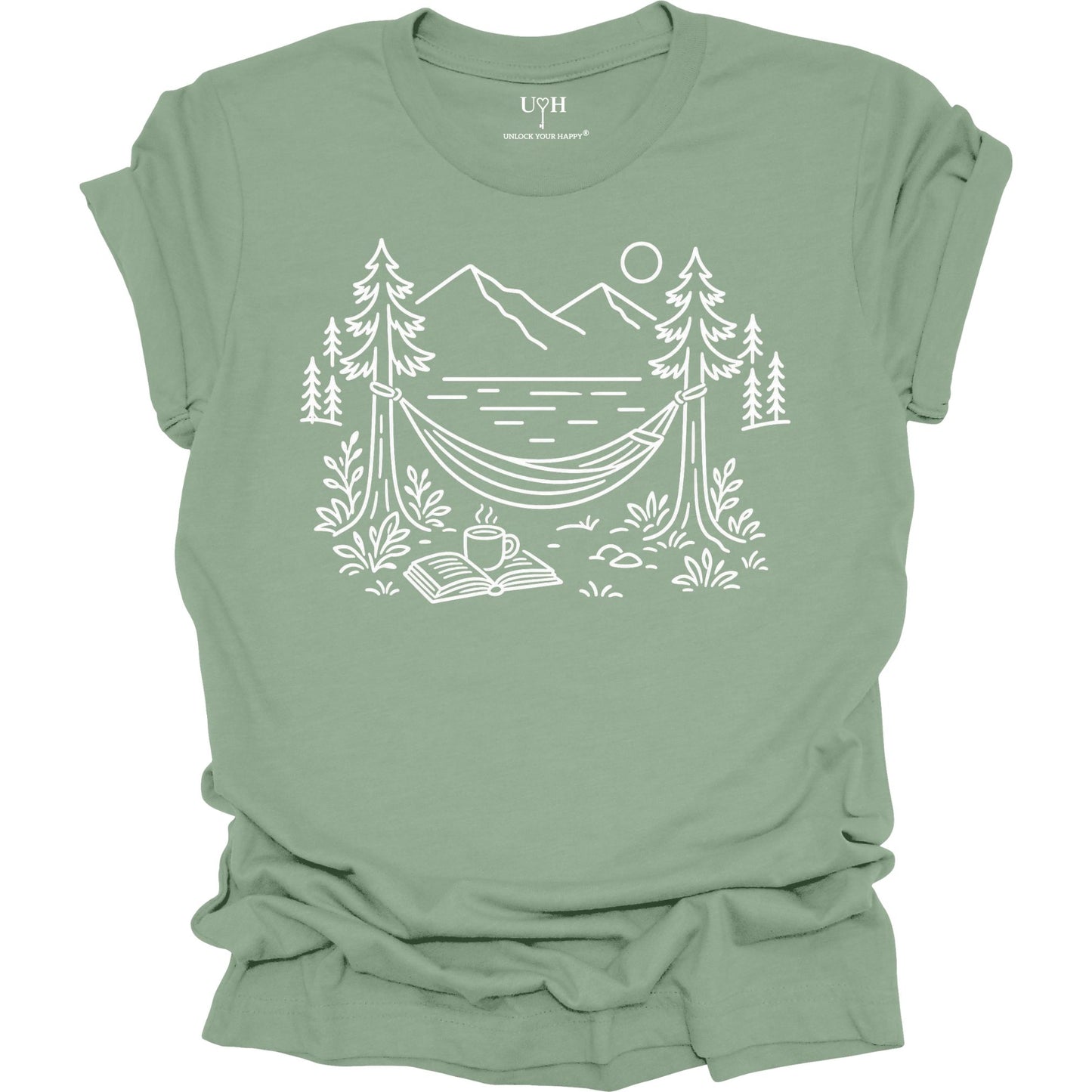 Sage unisex t-shirt with a white line art hammock scene featuring mountains, trees, a lake, coffee cup, and open book, plus ‘unlock your happy’ on the sleeve.